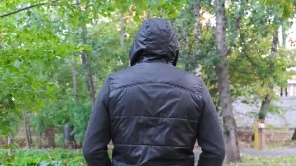 Un homme portant une capuche noire. Promenade dans le parc le soir .