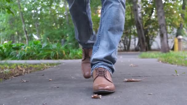 Kilátás a férfiak sétáló lábak kék farmer, barna bőr cipő. — Stock videók