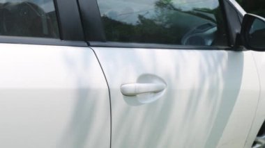 Beyaz, modern bir arabanın kapısını açar.