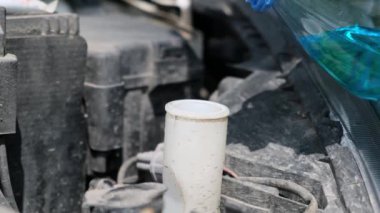 Adam özel temizlik malzemeleri şişesini araba temizleme tankına boşaltıyor.