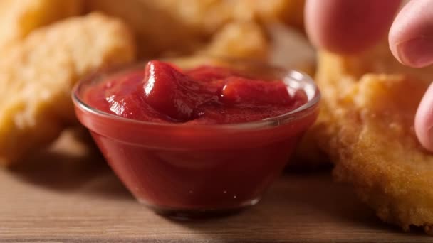 Gros plan de la main masculine Plongée pépite de poulet dans la sauce ketchup. — Video