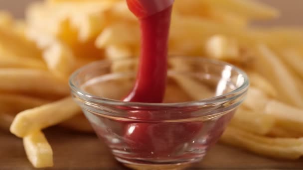 Verser le ketchup aux tomates avec des frites sur le fond, gros plan — Video