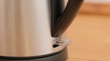 Mutfaktaki elektrikli çaydanlığın düğmesini açacak bir el. Kapat.