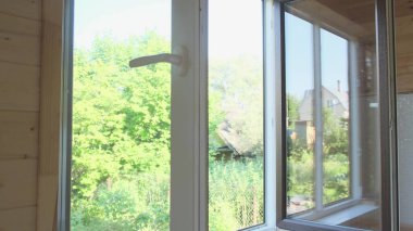 Bir adam beyaz plastik pencereyi kapı kolundan kapatır..