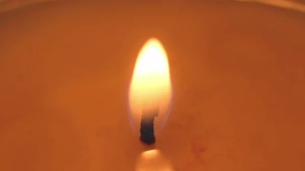 Hermoso fuego de una vela en una habitación oscura, una vela amarilla cálida — Foto de Stock