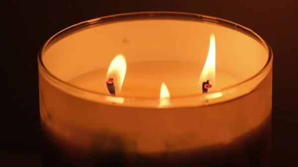 Belo fogo de uma vela em um quarto escuro, uma vela amarela quente — Fotografia de Stock