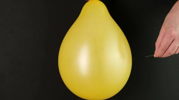 Vatten ballong poppas med hjälp av nål på svart — Stockfoto