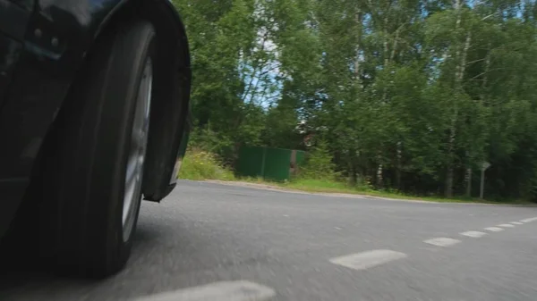 Schwarzes Auto fährt mit Geschwindigkeit über die Straße auf dem Asphalt, Blick vom Lenkrad. — Stockfoto