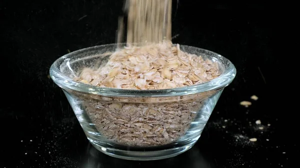 La farine d'avoine sèche est versée dans un bol en verre. Gros plan — Photo
