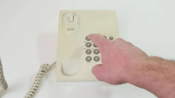 Hand picks up the phone dials the number , old push-button office. Close up.