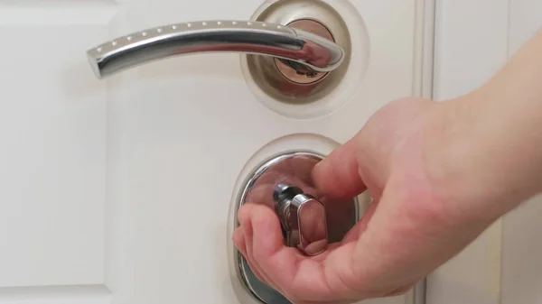 Hand opening and closing door silver handle. Close-up of doorknob.