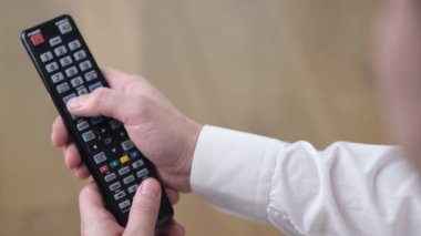Bir insan akıllı bir televizyon izler ve modern siyah uzaktan kumanda kullanır. Kapat.