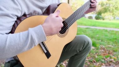 Parkta çalan bir adamın gitarını yakından çek. Kapat.