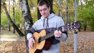 Parkta çalan bir adamın gitarını yakından çek. Kapat.