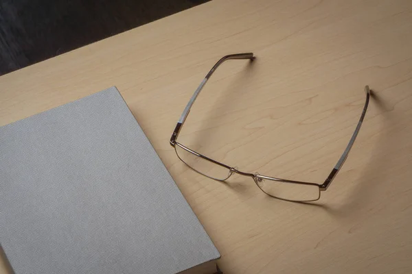 Серый дневник и очки на коричневом столе, избирательный фокус. Концепция стола — стоковое фото