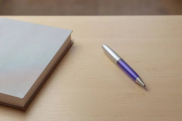 Серый дневник, синяя ручка и очки на коричневом столе, избирательный фокус. Концепция стола — стоковое фото