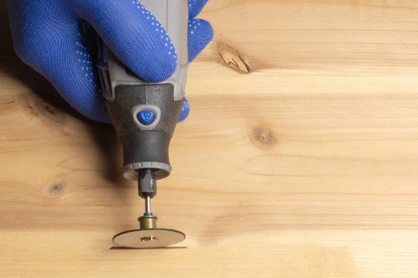 Timmerman in blauwe beschermende handschoenen omgaat met houten dremel — Stockfoto