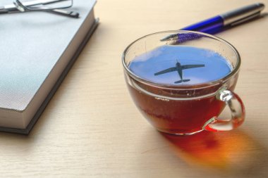 Ofis masasında gökyüzünde uçağın bir yansıması ile bir fincan çay