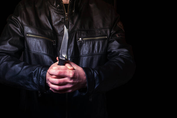 Человек в черной кожаной куртке с ножом в руке
