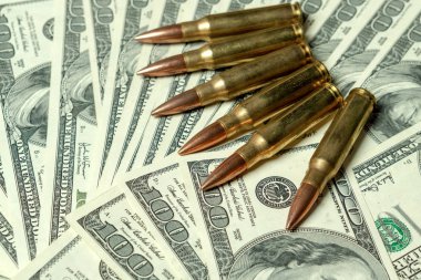 Dolarların üzerinde tüfek mermileri. Suç kavramı, kiralık katil, ücretli suikastçı, terörizm, savaş, küresel silah ticareti, silah satışı. Yasadışı avcılık, kaçak avcılık