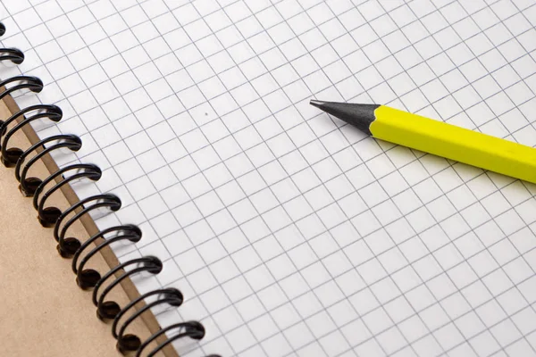 Yellow pencil on a notebook with sheets in a cage on a wooden table — Stock Photo, Image