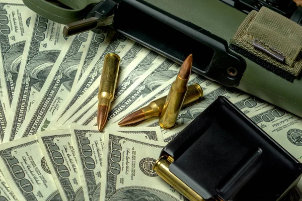 Rifle, magazine and cartridges on hundred dollar bills. Concept for crime, contract killing, paid assassin, terrorism, war, global arms trade, weapons sale. Illegal hunting, poaching