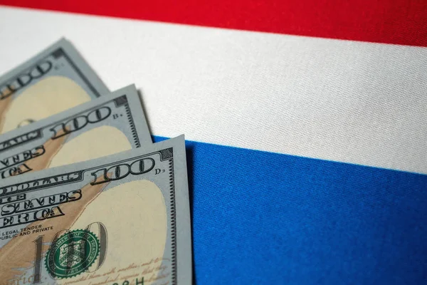 Нідерландський національний прапор і доларові купюри. Концепція бізнесу та фінансів, м'який фокус. — стокове фото