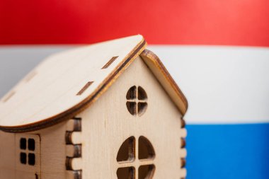 Arka planda Hollanda bayrağı olan küçük ahşap bir ev. Gayrimenkul kavramı, yumuşak odaklanma