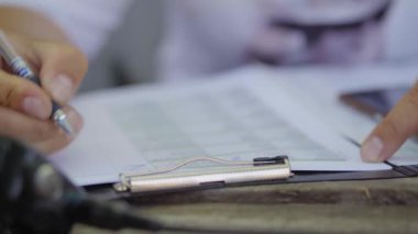 Bir adam doküman ya da anket doldurur, bir erkeğin elleri yakındır.