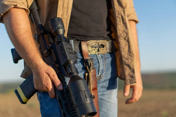 Een geweer in een mensenhand, close-up. Jager met een wapen op jacht tegen de achtergrond van een prachtig zomerlandschap — Stockfoto