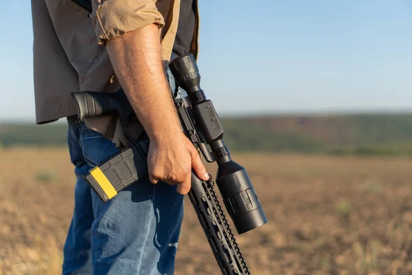 Een geweer in een mensenhand, close-up. Jager met een wapen op jacht tegen de achtergrond van een prachtig zomerlandschap — Stockfoto