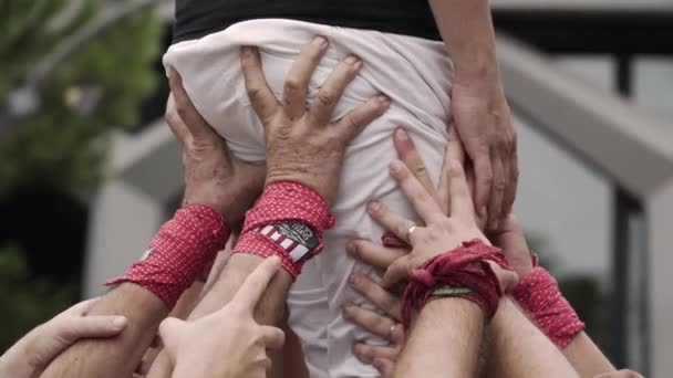 Castellers タワーのそばに ベースから手の多くは つのチーム メンバーから体を保持しています — ストック動画