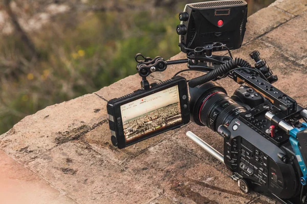 プロのカメラは 都市の景色を記録です ファインダーは開くと異なるビデオ パラメーターを表示します 岩の上にカメラを配置します ロイヤリティフリーのストック画像