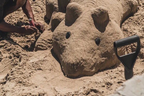 Someone works making sand sculptures. This sand figure has the shape of a mouse.