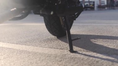 Birisi bir motosiklet üzerinde alır ve destek stand kaldırır.
