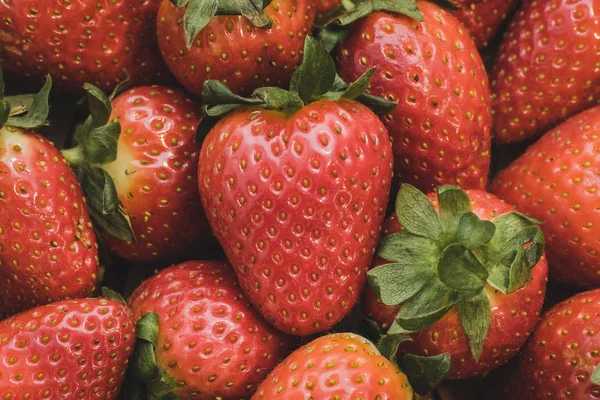 Un primer plano de un montón de fresas. Las fresas centrales recuerdan a un corazón porque su forma . — Foto de Stock