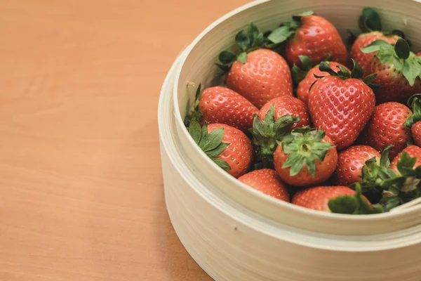 Una cesta llena de hermosas fresas encima de una mesa de madera. Están en el punto perfecto de maduración . — Foto de Stock