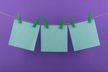 notlar ve yeşil renk hatırlatmalar için not defteri kağıt levhalar dekoratif yeşil clothespins ile bağlanmış mor bir arka plan üzerinde bir ip üzerinde asmak