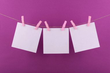 notlar için not defteri beyaz levhalar ve dekoratif pembe keten clothespins ile sabitlenmiş beyaz renk hatırlatmalar bir leylak arka plan üzerinde bir ip üzerinde asmak