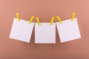 notlar ve dekoratif sarı clothespins ile sabitlenmiş beyaz renk hatırlatmalar için not defteri beyaz levhalar kahverengi bir arka plan üzerinde bir ip üzerinde asmak