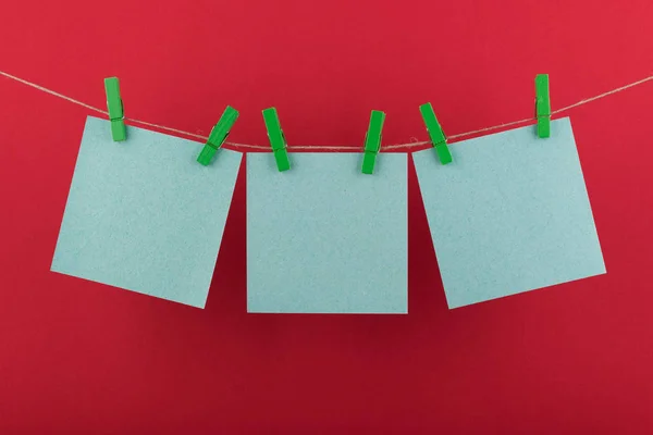 notlar ve yeşil renk hatırlatmalar için not defteri kağıt levhalar dekoratif yeşil clothespins kırmızı bir arka plan üzerinde bir ip üzerinde asılı sabitlenmiş
