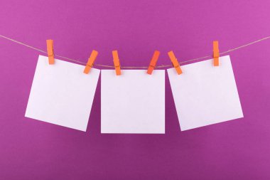 notlar ve dekoratif turuncu clothespins ile sabitlenmiş beyaz renk hatırlatmalar için not defteri beyaz levhalar bir leylak arka plan üzerinde bir ip üzerinde asmak