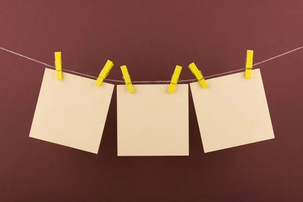 notlar ve hatırlatmalar için sarı not defteri kağıt levhalar, kahverengi bir arka plan üzerinde bir ip asılı dekoratif sarı clothespins ile sabitlenmiş