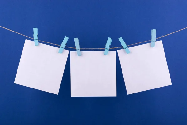 notlar ve beyaz renk hatırlatmalar için not defteri kağıt levhalar, mavi bir arka plan üzerinde bir ip üzerinde asılı dekoratif turuncu clothespins ile sabitlenmiş