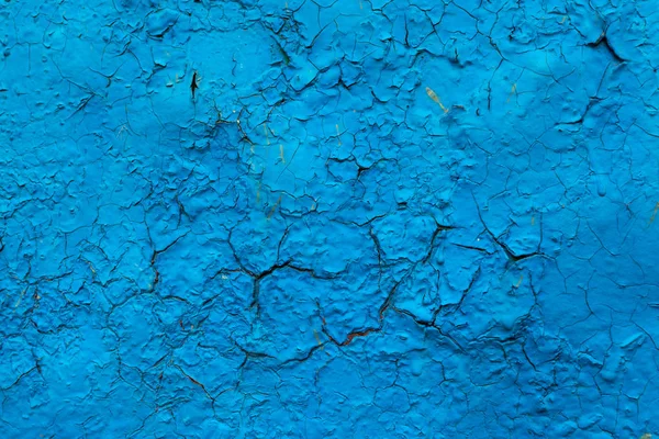 old rusty metal surface painted with peeling and cracked blue paint from time to time as an abstract background with large cracks