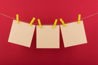 notlar ve hatırlatmalar için sarı defter kağıt levhalar, kırmızı bir arka plan üzerinde bir ip asılı dekoratif sarı clothespins ile sabitlenmiş