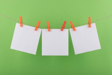 notlar ve hatırlatmalar için not defteri beyaz levhalar, dekoratif turuncu clothespins ile sabitlenmiş, açık yeşil bir arka plan üzerinde bir ip üzerinde asmak