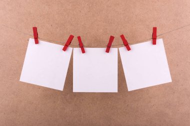 notlar ve hatırlatmalar için not defteri beyaz levhalar, dekoratif kırmızı clothespins ile sabitlenmiş, kahverengi bir arka plan üzerinde bir ip üzerinde asmak