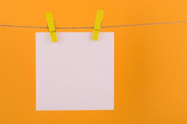 notlar ve beyaz renk hatırlatmalar için not defteri kağıt levhalar, dekoratif sarı clothespins ile sabitlenmiş sarı bir arka plan üzerinde bir ip üzerinde asmak