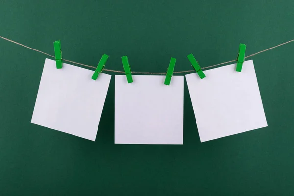 notlar ve hatırlatmalar için not defteri beyaz levhalar, dekoratif yeşil clothespins ile sabitlenmiş, yeşil bir arka plan üzerinde bir ip üzerinde asmak